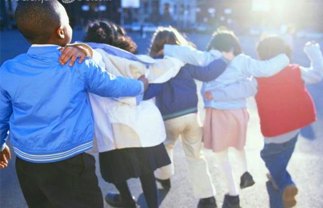 5 children hugging while walking on playground 